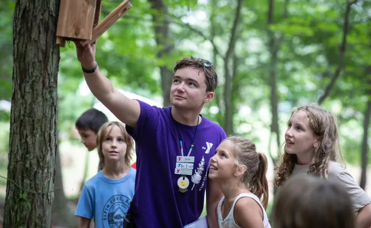 image of camp counselor showing campers a bird feeder