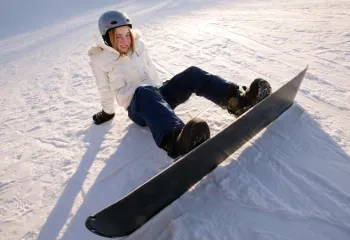 photo of young teen snowboarder sitting in the snow