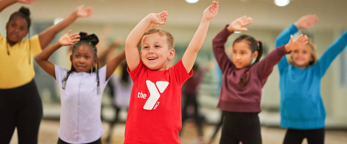 group of young kids smiling with their arms in the air