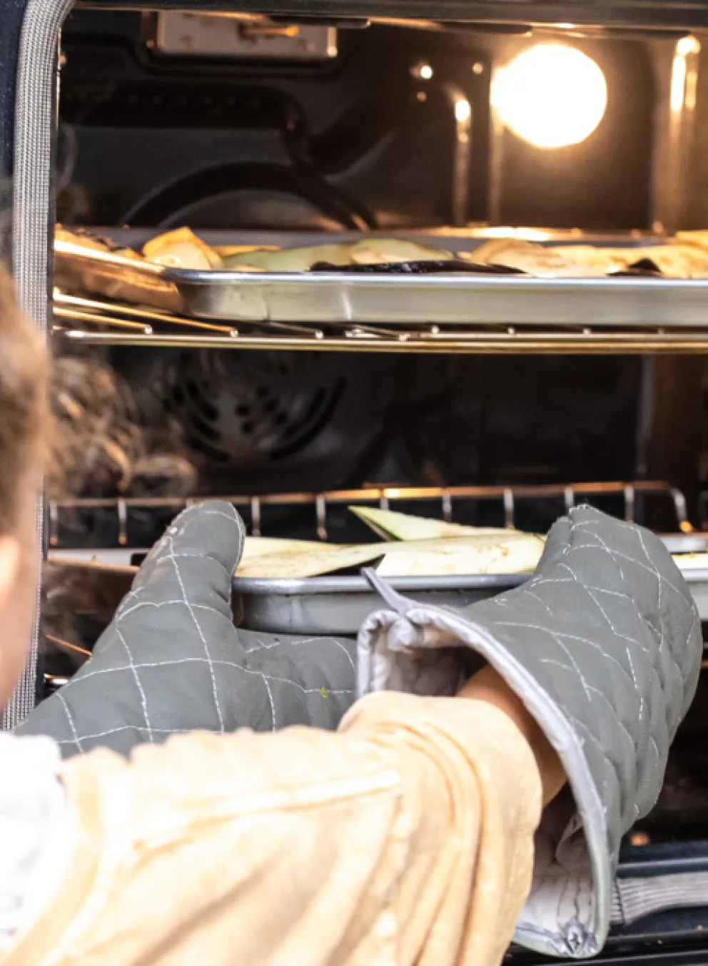 girl in kitchen removing food from oven