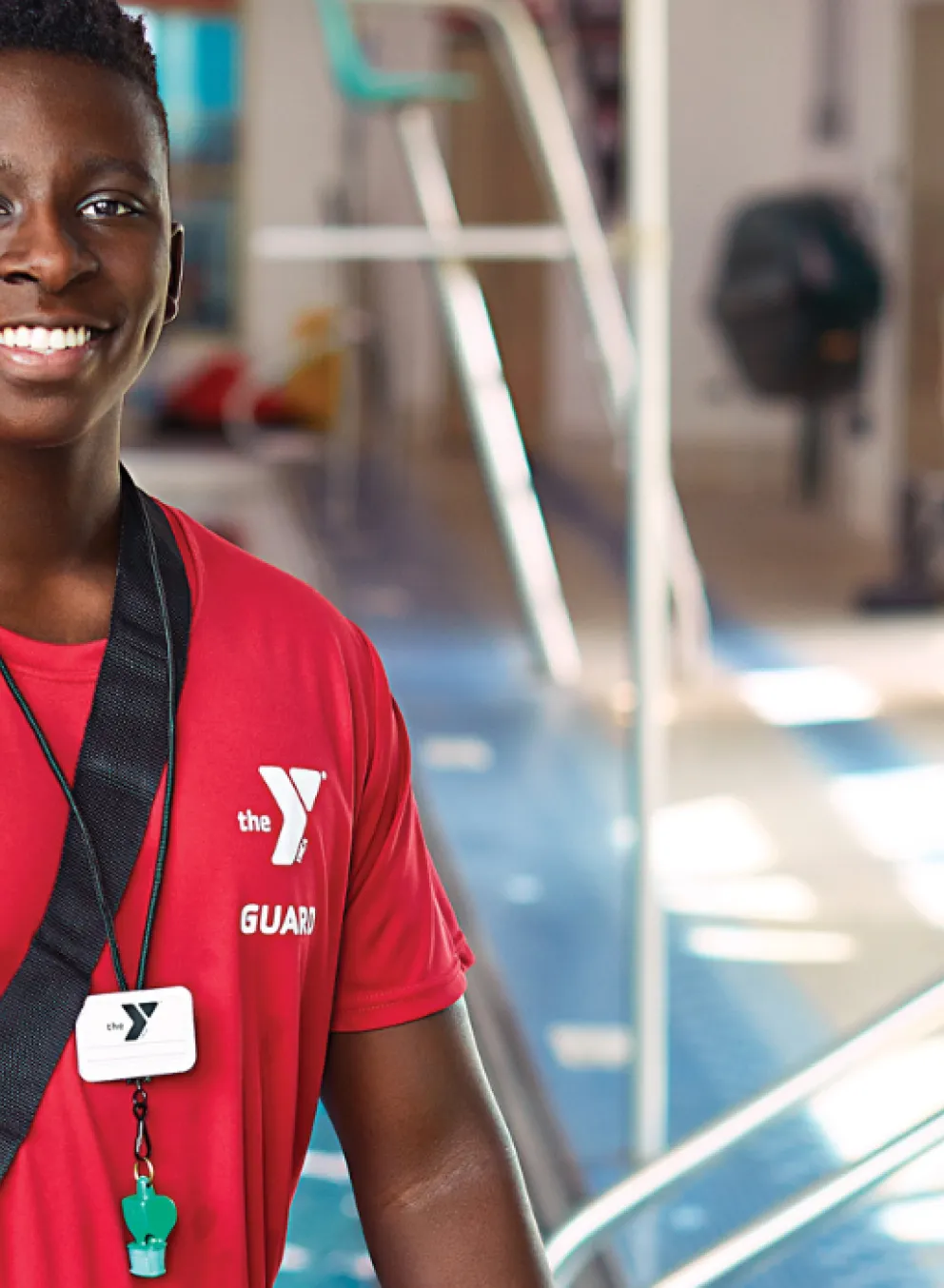teen lifeguard standing in front of the pool smiling
