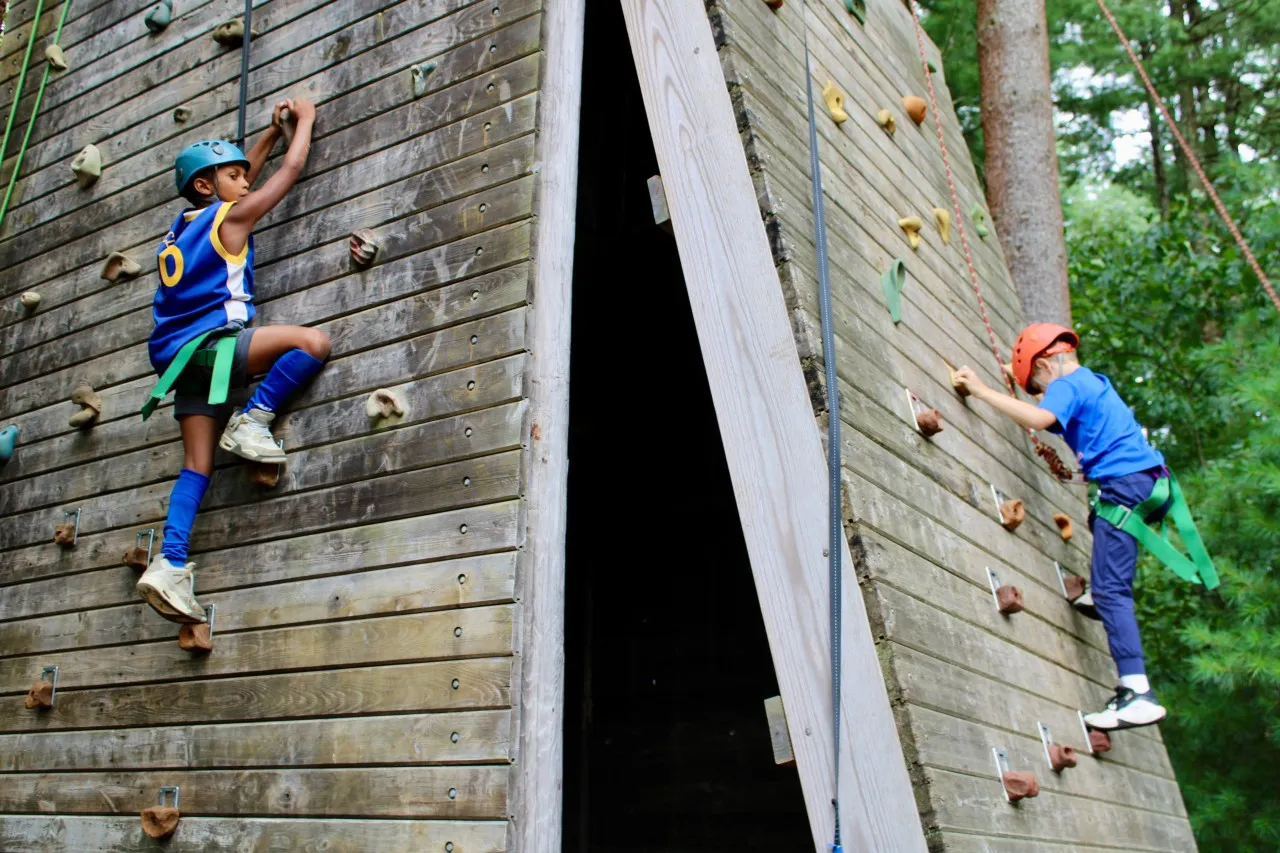 image of two boy climbing up an outdoor climbing wall