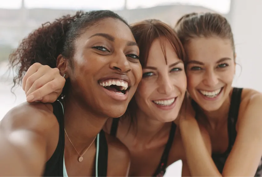 image of three women smiling with their arms around each other