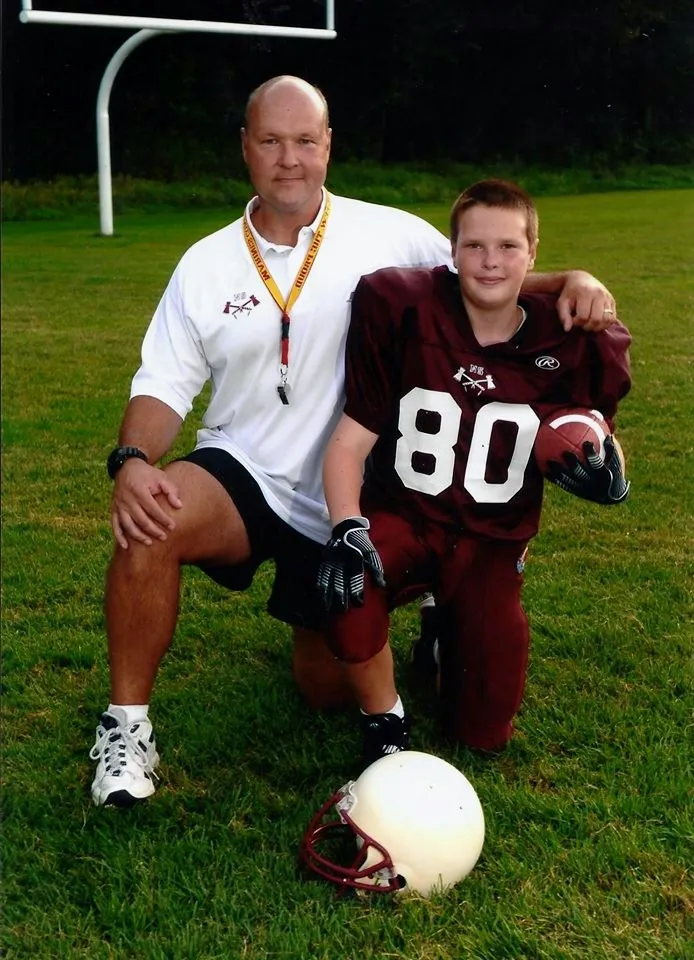 photo of father and son posing on football field