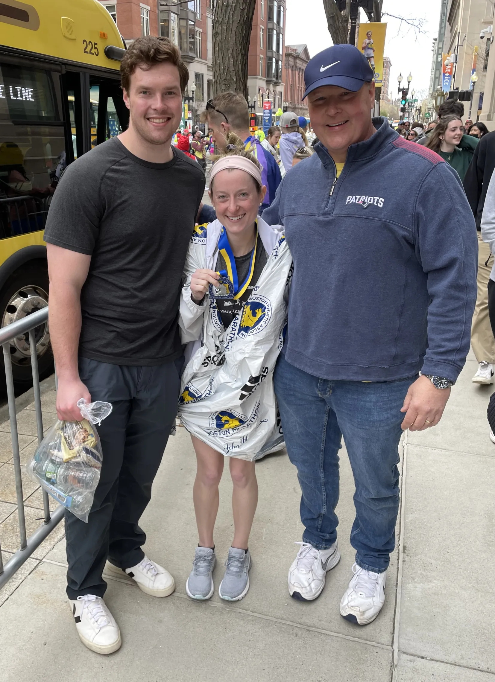 photo of three: two gentlemen posing with female marathon runner