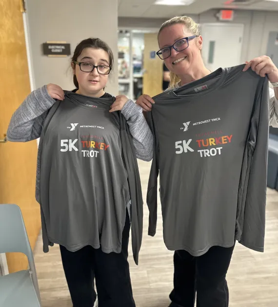 photo of two 5k treadmill turkey trot participants holding gray shirts