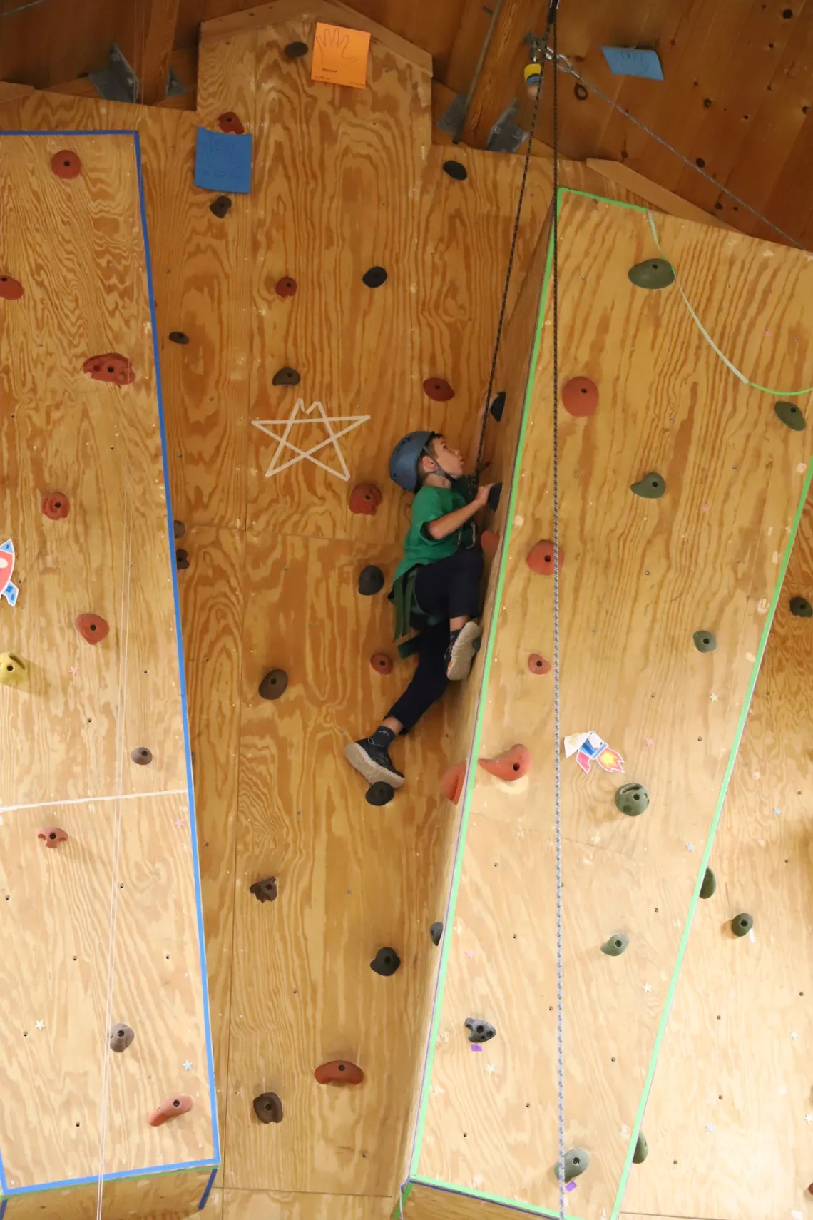 image of boy climbing to the top of a climbing wall