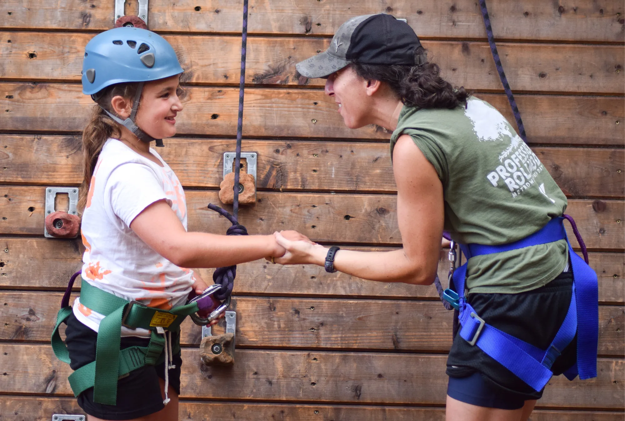 ymca staff member helping young girl at climbing wall