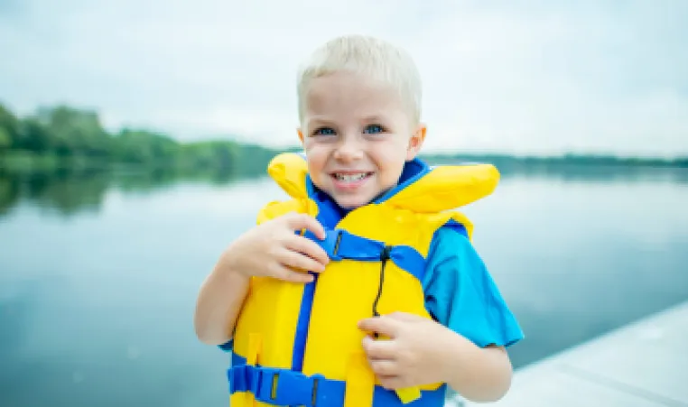 Little boy wears a lifejacket to demonstrate water safety