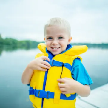 Little boy wears a lifejacket to demonstrate water safety